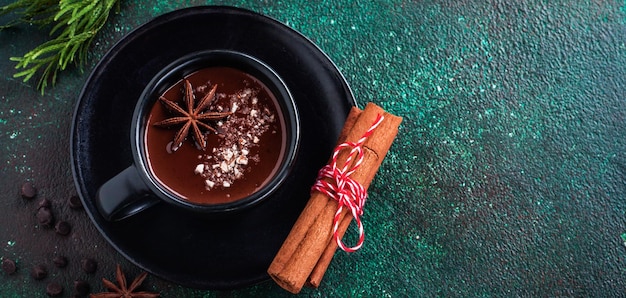 Cioccolata calda con anice e noci in tazza di ceramica nera su vecchio fondo di cemento verde scuro. Messa a fuoco selettiva.