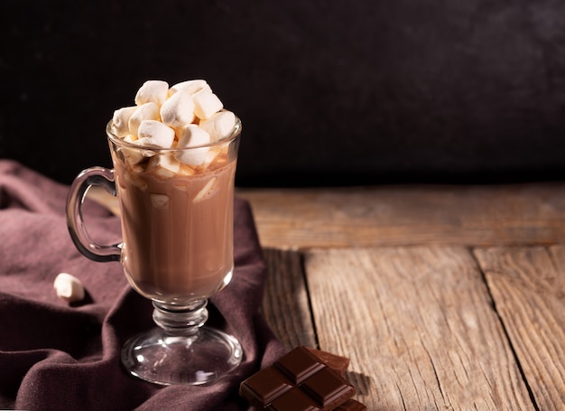 Cioccolata calda con cannella e marshmallow su fondo di legno