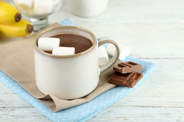 Cioccolata calda con marshmallow in tazza, su fondo in legno