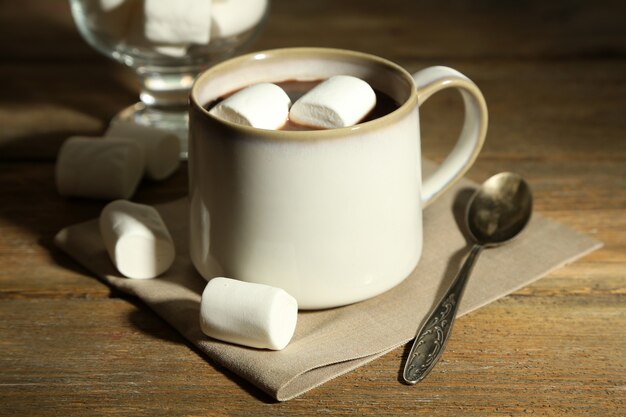 Cioccolata calda con marshmallow in tazza, su fondo in legno