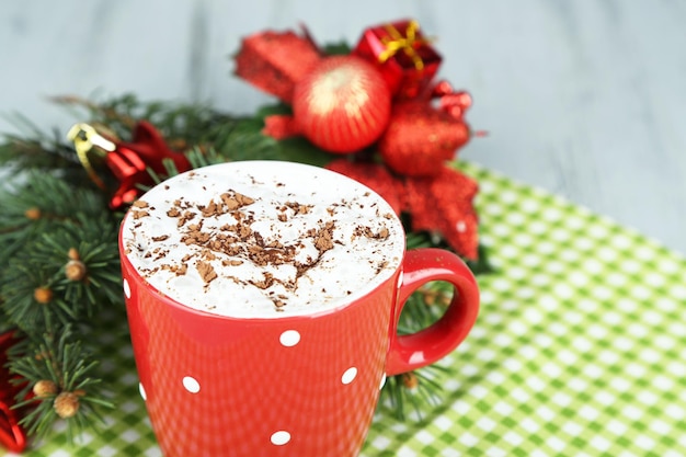 Cioccolata calda con panna in tazza colorata, su tovagliolo, su sfondo di decorazioni natalizie