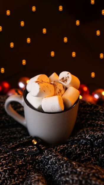 Cioccolata calda di Natale con marshmallow con luci bokeh. Messa a fuoco selettiva - foto verticale