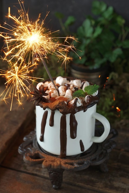 Cioccolata calda di Natale in una tazza bianca con marshmallow e gocce di cioccolato con stelle filanti su tavola di legno naturale, Sfondo di pietra verde e nera, Messa a fuoco selettiva, Verticale