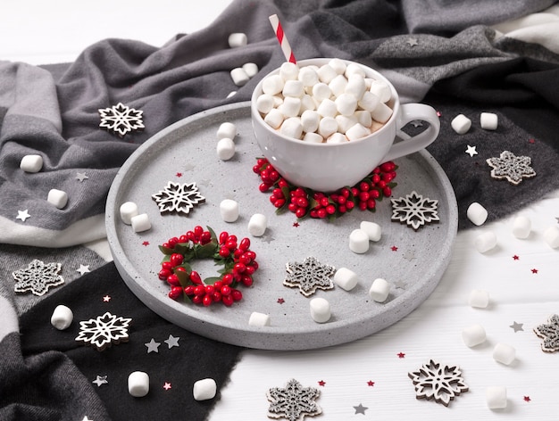 Cioccolata calda o caffè di Natale con la caramella gommosa e molle sulla tavola di legno bianca con le decorazioni di natale