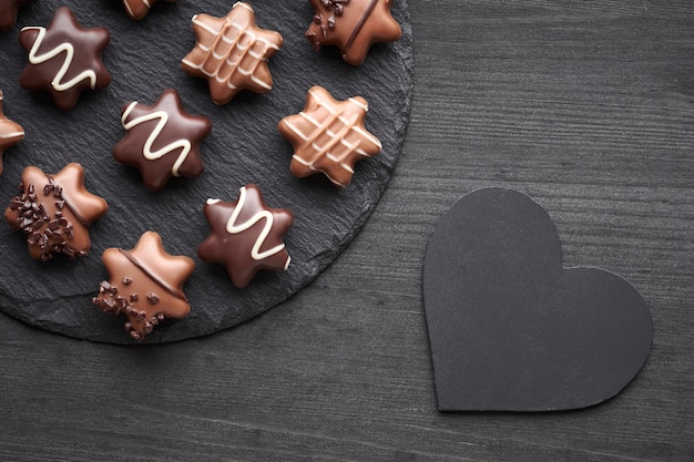 Cioccolatini a forma di stella su sfondo scuro con texture con il cuore