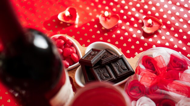 Cioccolatini e dolci su piatti a forma di cuore. Impostazione della tavola festiva per la data degli innamorati. Sfondo rosso