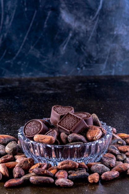 Cioccolatini su vassoio in vetro intagliato, fotografati su sfondo scuro.