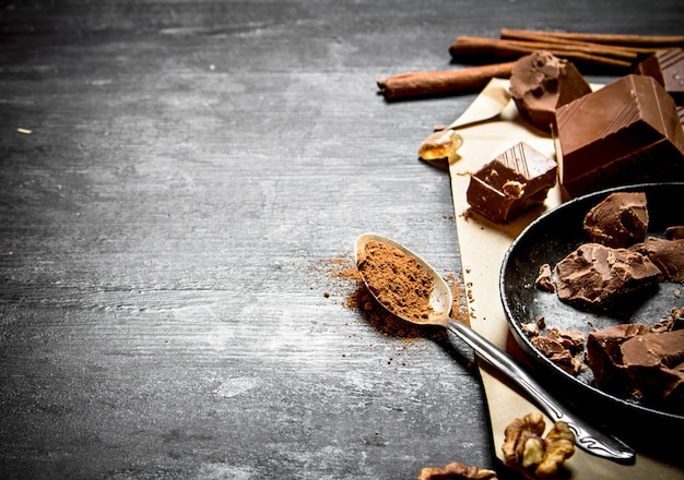 Cioccolato al latte con cacao. Su uno sfondo di legno nero.