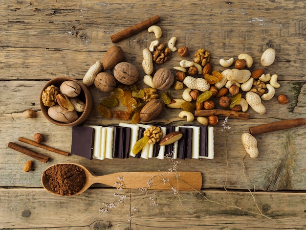 Cioccolato amaro e al latte, noci e altri dolci su un tavolo di legno.