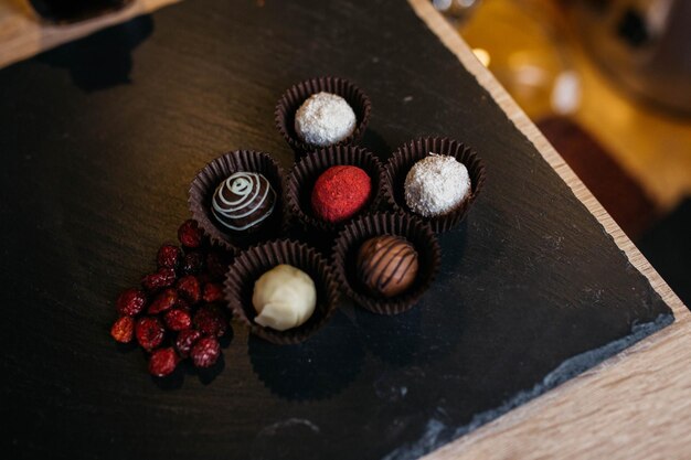 Cioccolato artigianale Vista dall'alto di varie praline di cioccolato Caramelle su tavola di legno Viburno essiccato a sinistra delle caramelle Vista dall'alto