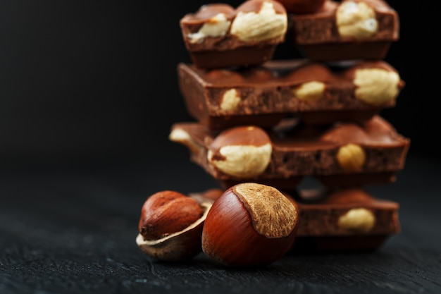 Cioccolato con nocciole a forma di torre, circondato da noci nel guscio e sbucciato.