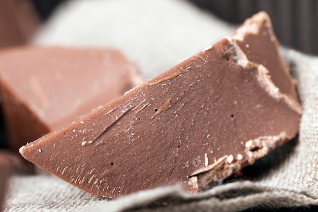 Cioccolato da prodotti a base di cacao e zucchero, primo piano delizioso cibo ipercalorico, cioccolato commestibile naturale, rotto in pezzi e briciole di cioccolato al latte