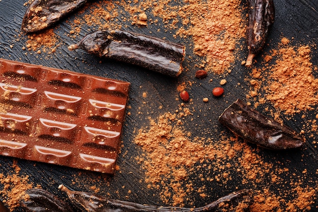 Cioccolato di carruba e polvere di frutta di carruba sulla superficie scura