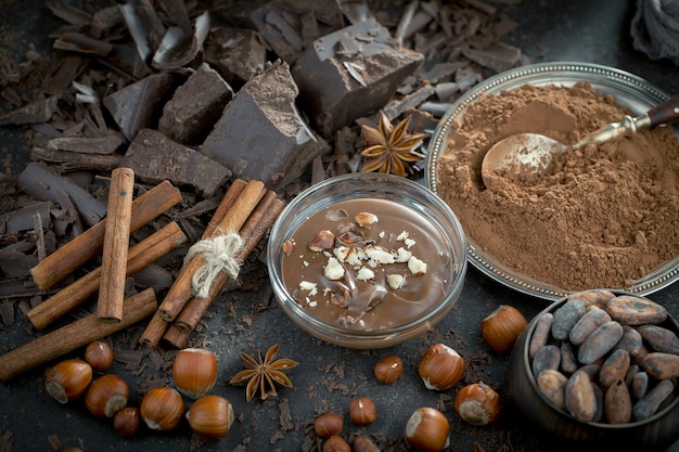 Cioccolato fondente in una composizione con fave di cacao e noci, su un vecchio sfondo.