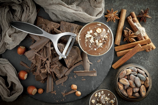 Cioccolato fondente in una composizione con fave di cacao e noci, su un vecchio sfondo.