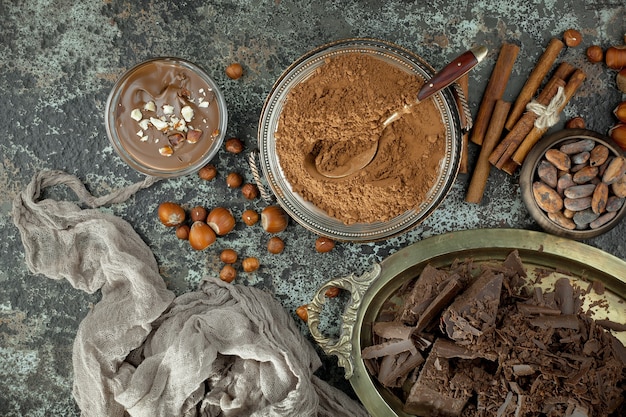 Cioccolato fondente in una composizione con fave di cacao e noci, su un vecchio sfondo.