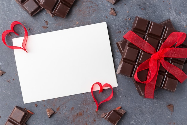 Cioccolato legato con un nastro rosso e un biglietto di auguri in bianco