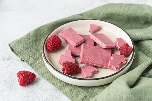 Cioccolato rosa o rubino, dessert moderno alla moda servito con lamponi su un piatto bianco