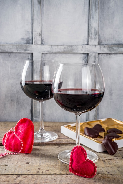 Cioccolato, rose, bicchieri di vino e scatola del cuore sul tavolo di legno