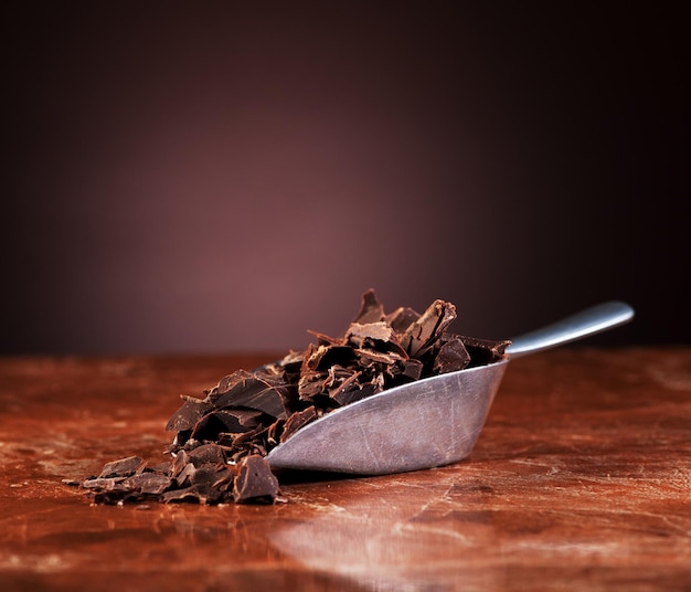 Cioccolato tritato in una paletta di metallo su fondo di marmo scuro