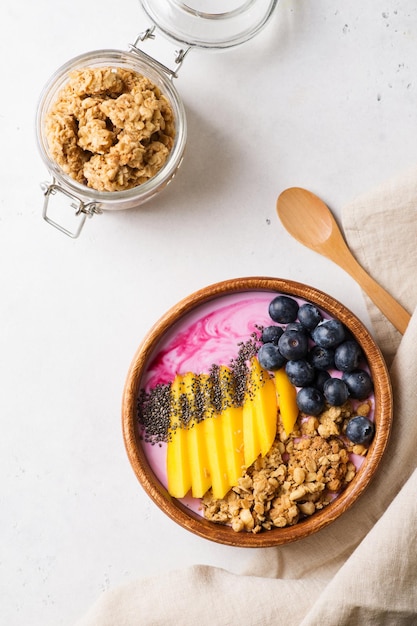 Ciotola Asai granola farina d'avena con mirtillo mango e semi di chia in piatto di legno su sfondo bianco spazio copia vista dall'alto