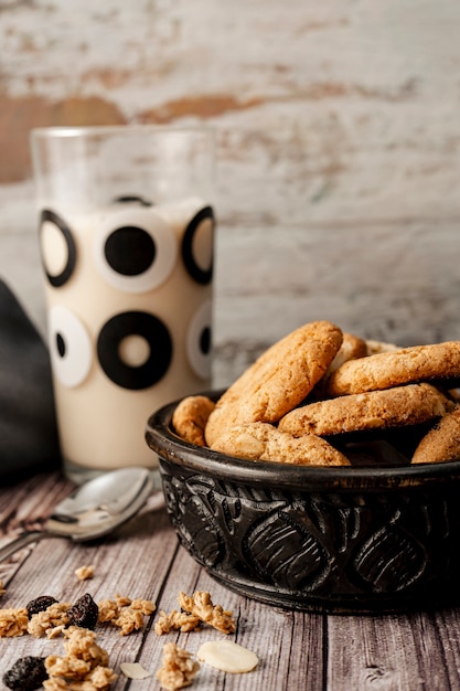 Ciotola con biscotti di farina d'avena fatti in casa e un bicchiere di latte dietro