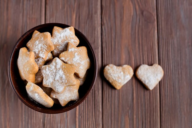 Ciotola con biscotti fatti in casa su uno sfondo marrone e due cuori su di esso