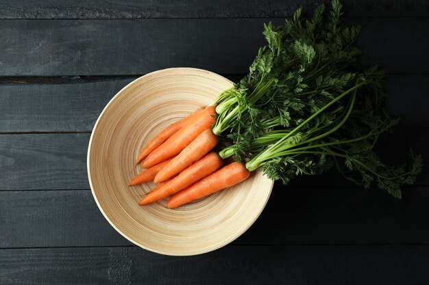 Ciotola con carota fresca su fondo di legno scuro