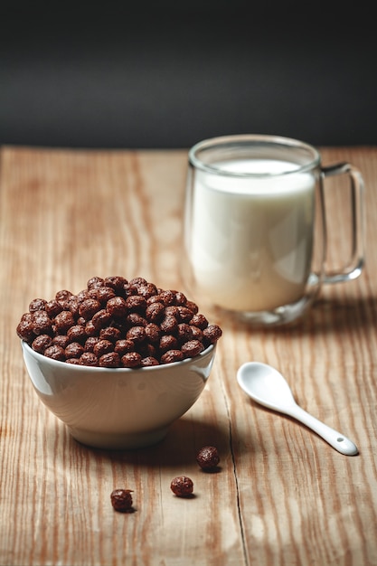 Ciotola con cereali per la colazione veloce al cioccolato e bicchiere di latte