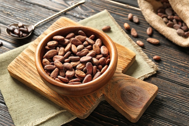 Ciotola con chicchi di cacao aromatici su uno sfondo di legno