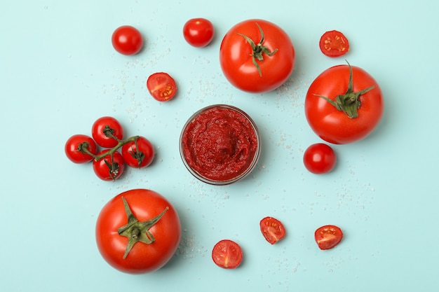 Ciotola con concentrato di pomodoro, pomodori e sale su sfondo blu