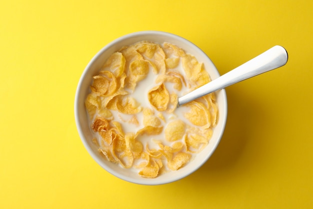 Ciotola con cornflakes e latte su sfondo giallo