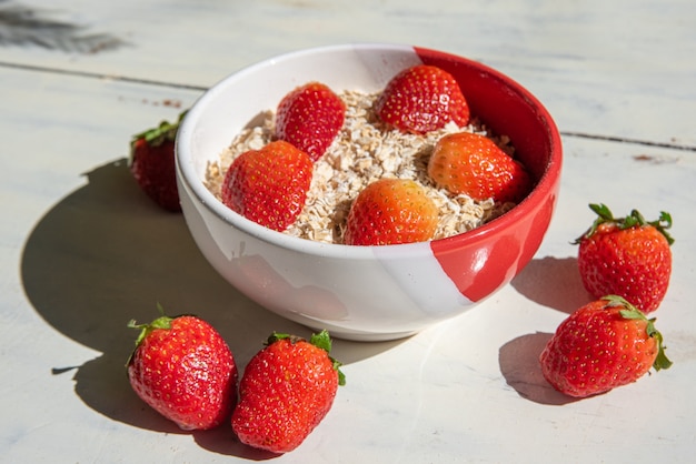 ciotola con fiocchi d'avena e fragole intorno