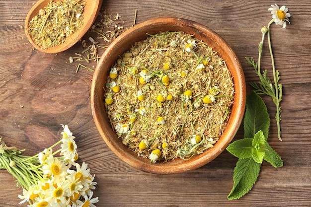 Ciotola con fiori di camomilla essiccati e macinati su fondo di legno