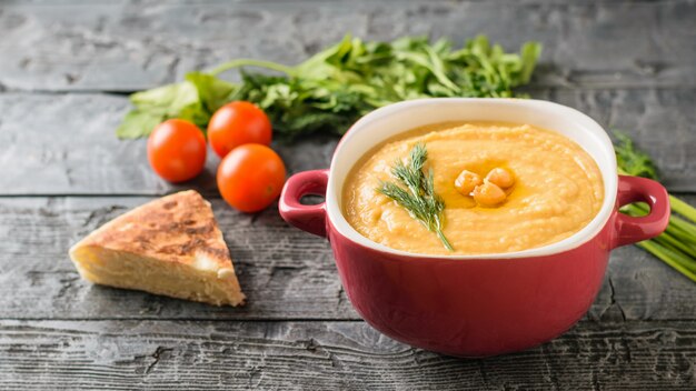 Ciotola con hummus, prezzemolo, pomodori, erbe e limone sul tavolo rustico