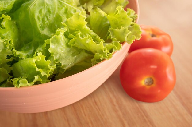 Ciotola con insalata di pomodori e lattuga su fondo di legno