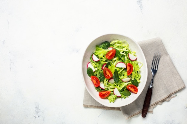 Ciotola con insalata fresca vegetariana. Cibo sano, pranzo dietetico. Vista dall'alto su uno sfondo bianco.