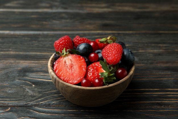 Ciotola con mix di frutti di bosco su legno