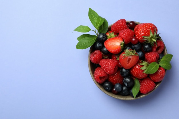 Ciotola con mix di frutti di bosco su violetta