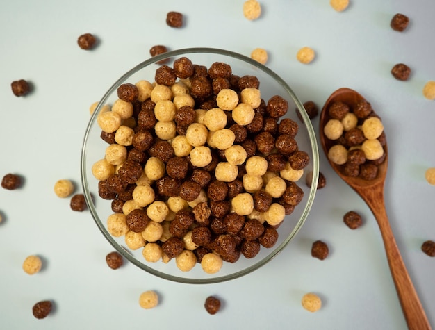 Ciotola con palline di cereali al cioccolato su sfondo blu Concetto di colazione sana