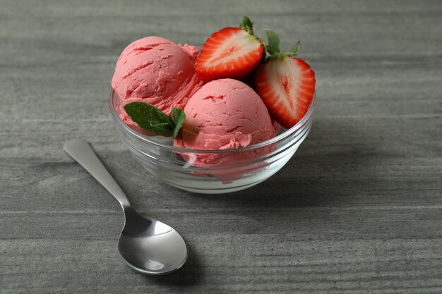 Ciotola con palline di gelato alla fragola sulla tabella strutturata grigia