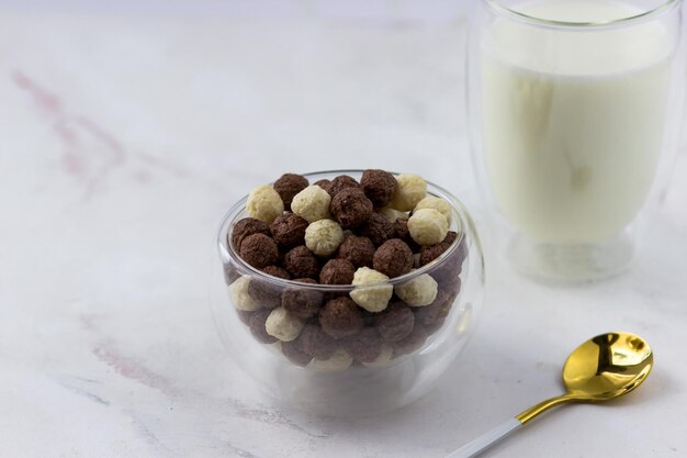 Ciotola con palline di vaniglia e cioccolato su sfondo bianco Snack e un bicchiere di latte colazione veloce