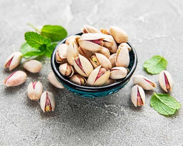 Ciotola con pistacchi su una superficie di cemento grigio