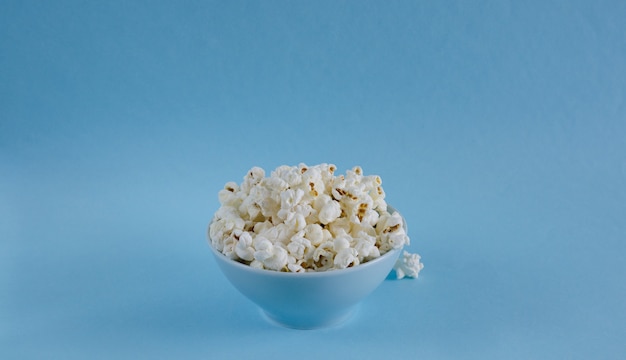 Ciotola con popcorn su sfondo blu.