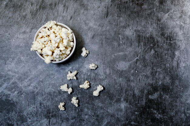 Ciotola con popcorn su sfondo grigio, vista dall'alto.