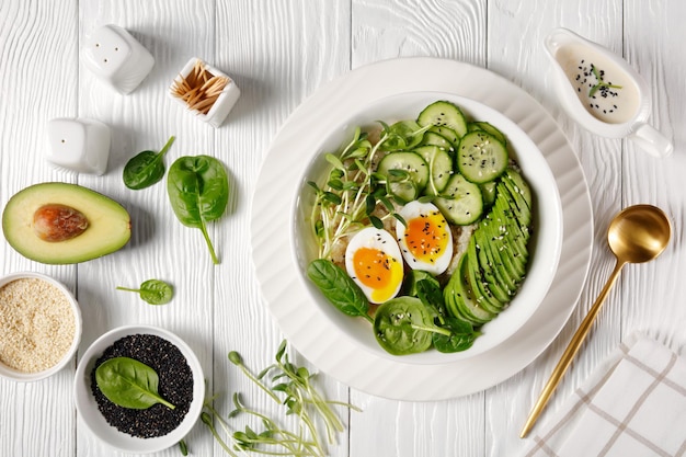 Ciotola con quinoa, microgreens di girasole, cetriolo, avocado, spinaci e uova sode con tuorlo che cola servito con salsa tahini, piatto, cucina turca