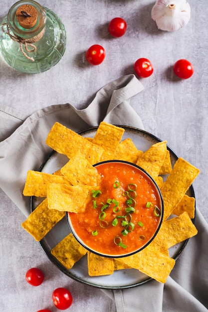 Ciotola con salsa di pomodoro messicana e patatine di mais sul piano del tavolo e vista verticale