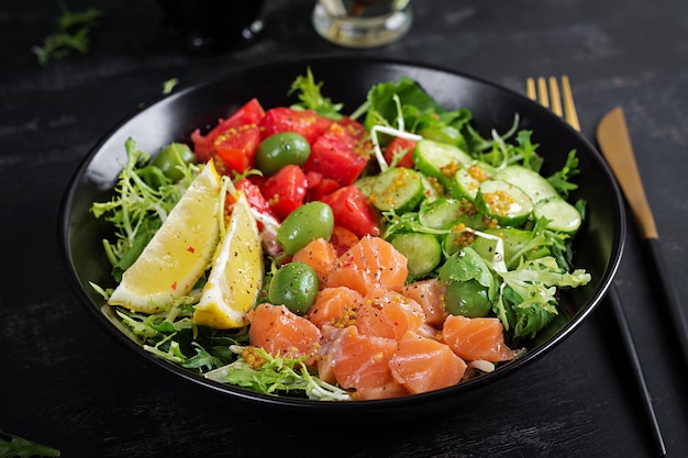 Ciotola da pranzo per dieta chetogenica o paleo con salmone salato pesce limone cetriolo olive pomodori lattuga verde insalata e miele condimento alla senape Tendenza alimentare sana