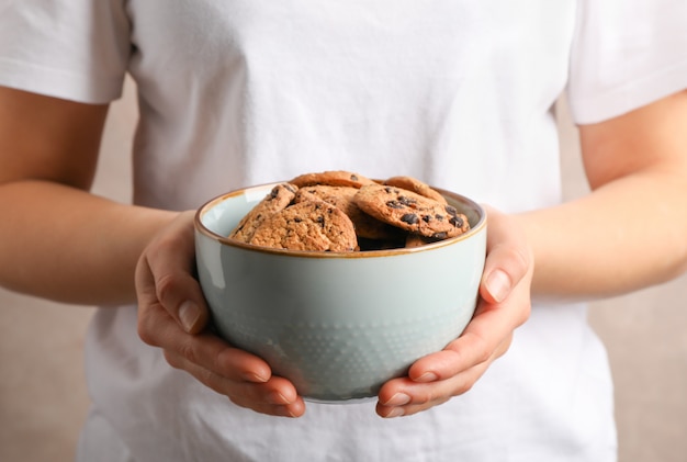 Ciotola della tenuta della donna con i biscotti di pepita di cioccolato saporiti, primo piano