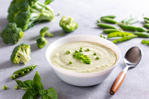 Ciotola di broccoli e zuppa di crema di piselli su uno sfondo di cemento chiaro